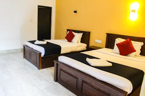 A large double bed and a single bed with red cushions against a warm yellow wall